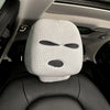 A white knitted ski mask car headrest cover placed on a black car seat.