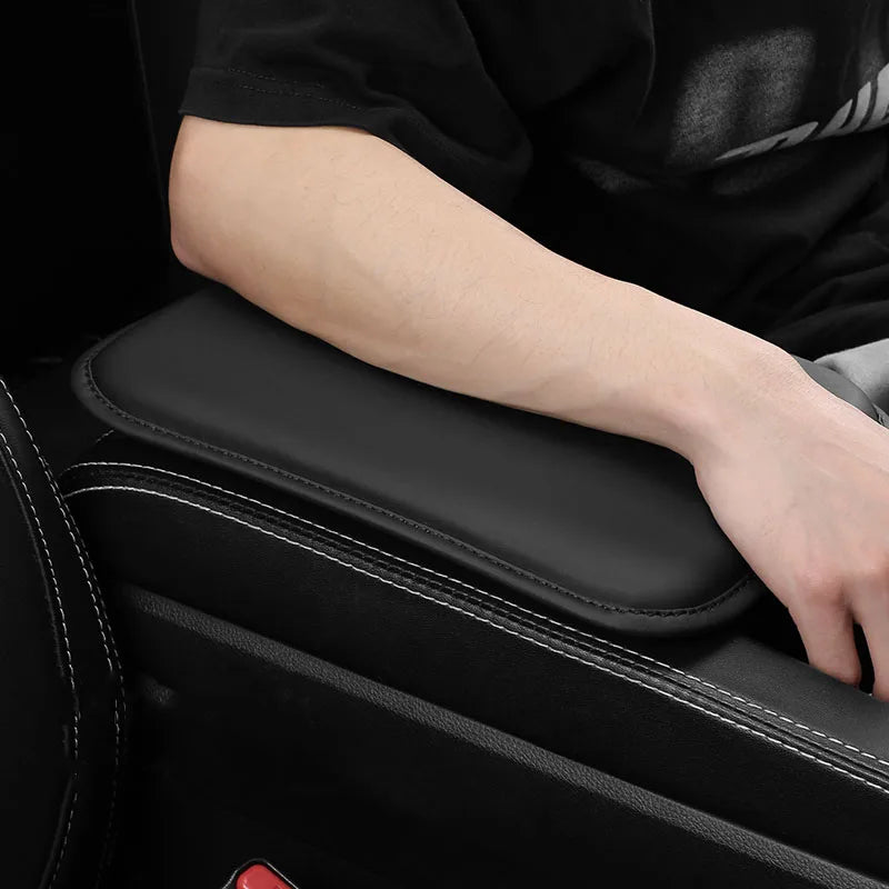 Gros plan sur une housse de repose-bras noire pour voiture avec couture et un bras posé dessus.