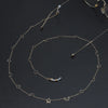 Gold chain necklace featuring a star and moon pendant, displayed against a dark background.