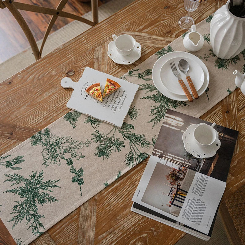 A classic gingham table runner with green foliage patterns is laid on a wooden table with white tableware.