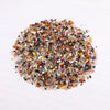 A pile of mixed natural crystal gravel stones and gemstone chips in various colors like amber, red, green, and brown.