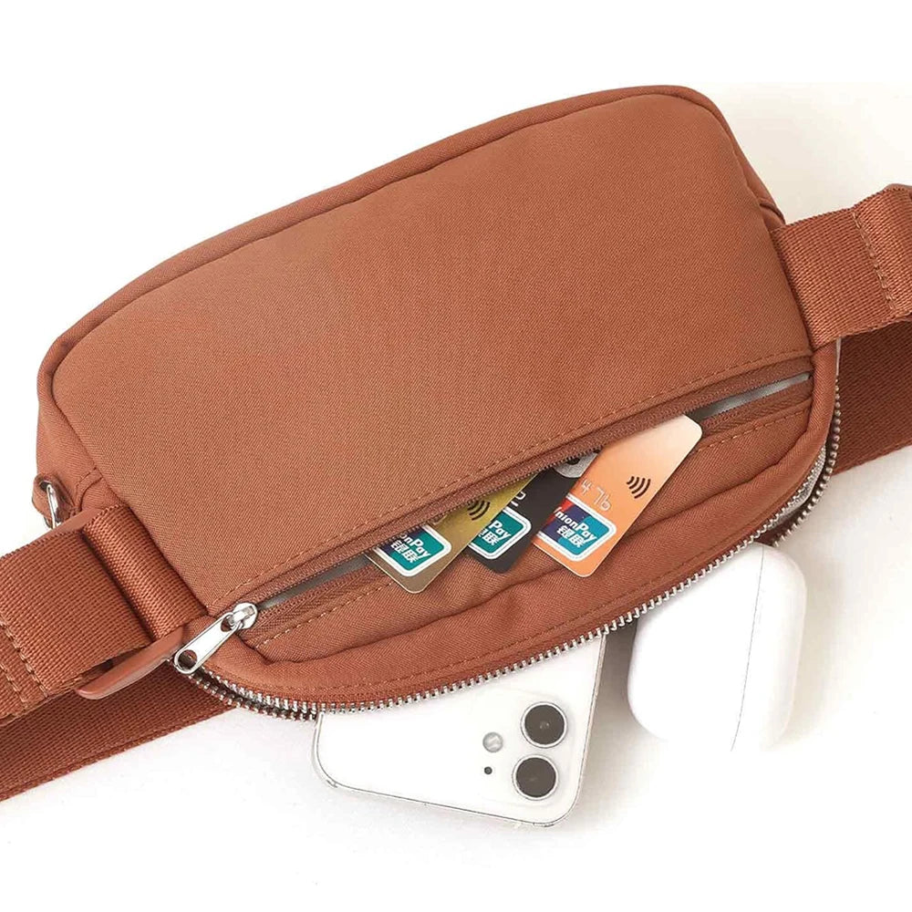 A brown nylon waist pack with a zippered phone pocket and a white wireless earbud is shown.