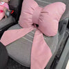 A pink butterfly bow tie neck pillow with a matching fabric cover is shown on a gray chair.