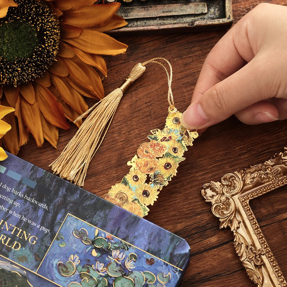 A vintage metal bookmark with an artistic hollow design and golden tassel resting on a wooden surface.