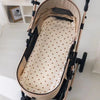 A beige baby stroller seat cushion with padded support and a patterned fabric lining is shown on a stand.