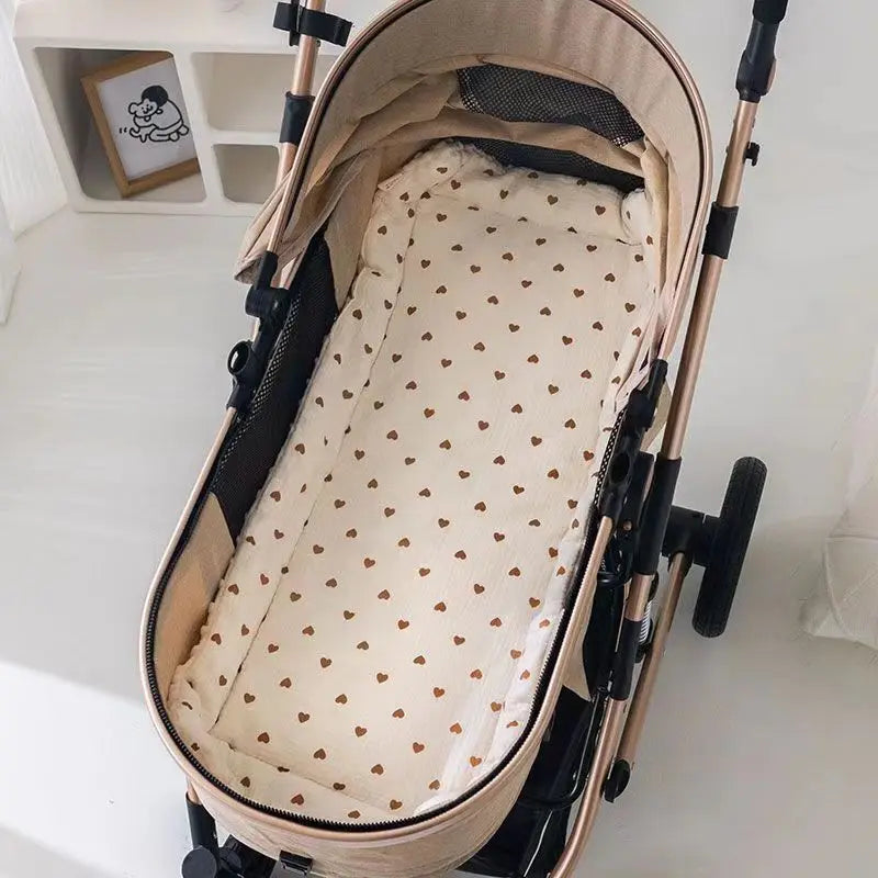 A beige baby stroller seat cushion with padded support and a patterned fabric lining is shown on a stand.