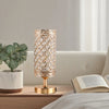 A tall, textured crystal table lamp with a gold base and diamond pattern sits on a wooden surface next to a book.