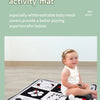A baby is playing on a black and white mesh fabric activity mat with various hanging toys.