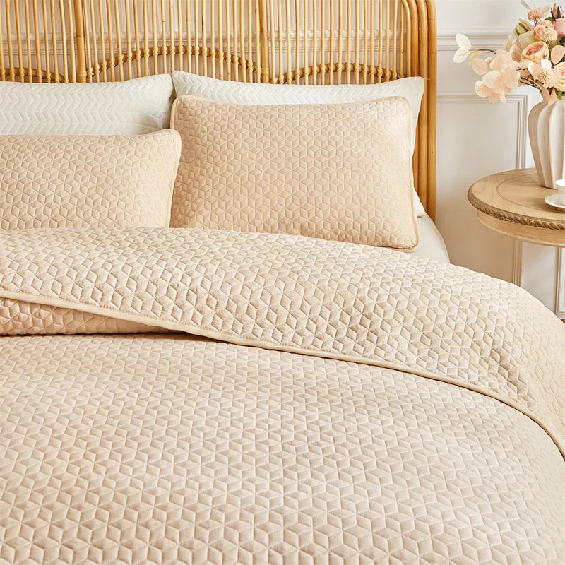 Beige plaid queen bedspread set with matching pillow shams displayed on a light wood headboard.