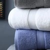 A stack of folded bath towels in shades of gray, white, and blue.