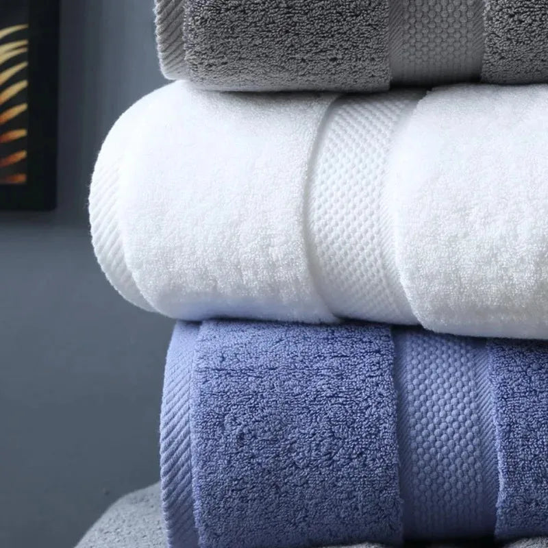 A stack of folded bath towels in shades of gray, white, and blue.