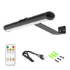 A black cordless rechargeable picture light fixture with a remote control and power cord.