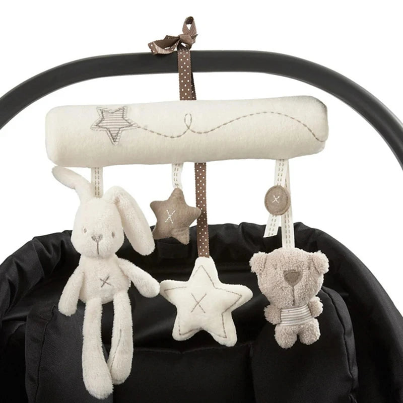 A soft plush bunny rattle toy with a star decoration hanging from a black strap.