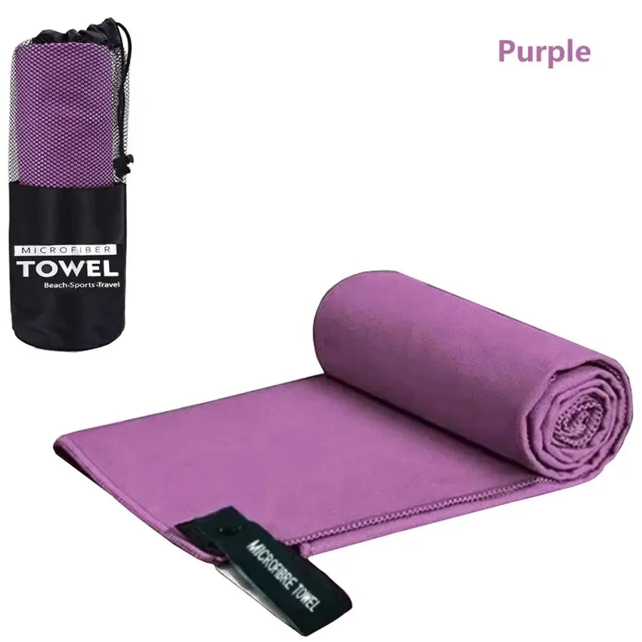Purple microfiber sports towel rolled up and a separate towel packaged in a black pouch
