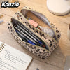 A leopard print double-zip pencil case is shown open, revealing pens and pencils inside on a wooden surface.