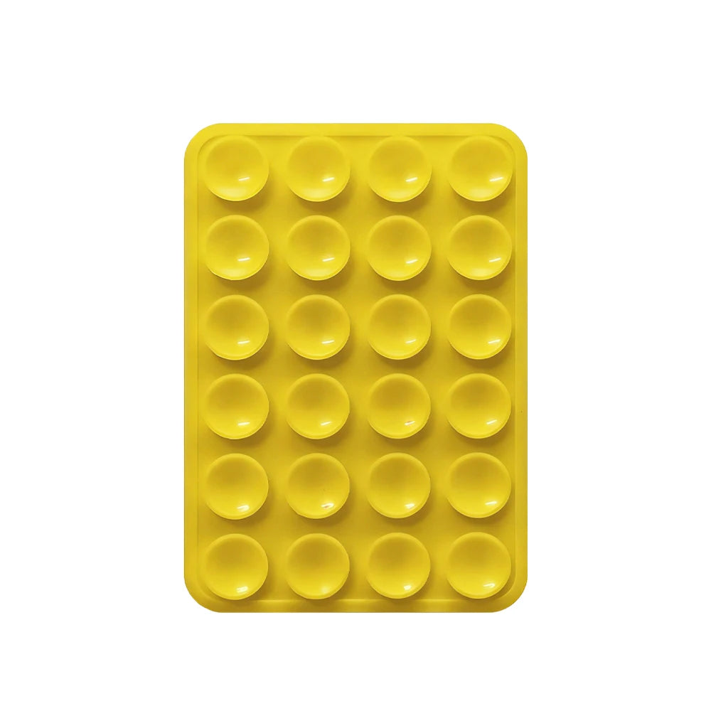 A yellow silicone suction pad with multiple circular indentations for phone mounts.