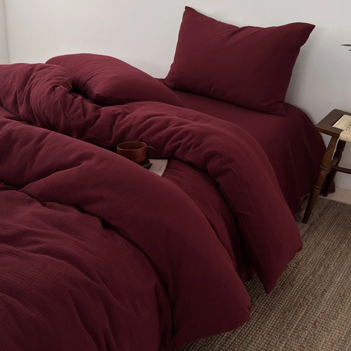 Dunkelburgunderner gekräuselter Bettbezug- und Kissen-Set auf einem Bett.