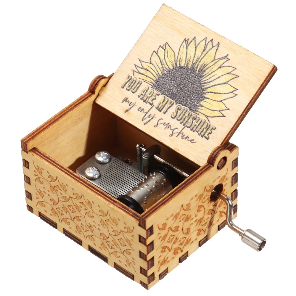 A vintage hand-cranked wooden music box with a lid featuring a sunflower design and a small metal crank.
