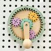 A wooden busy board featuring colorful gears and a wooden knob for fine motor skill development.