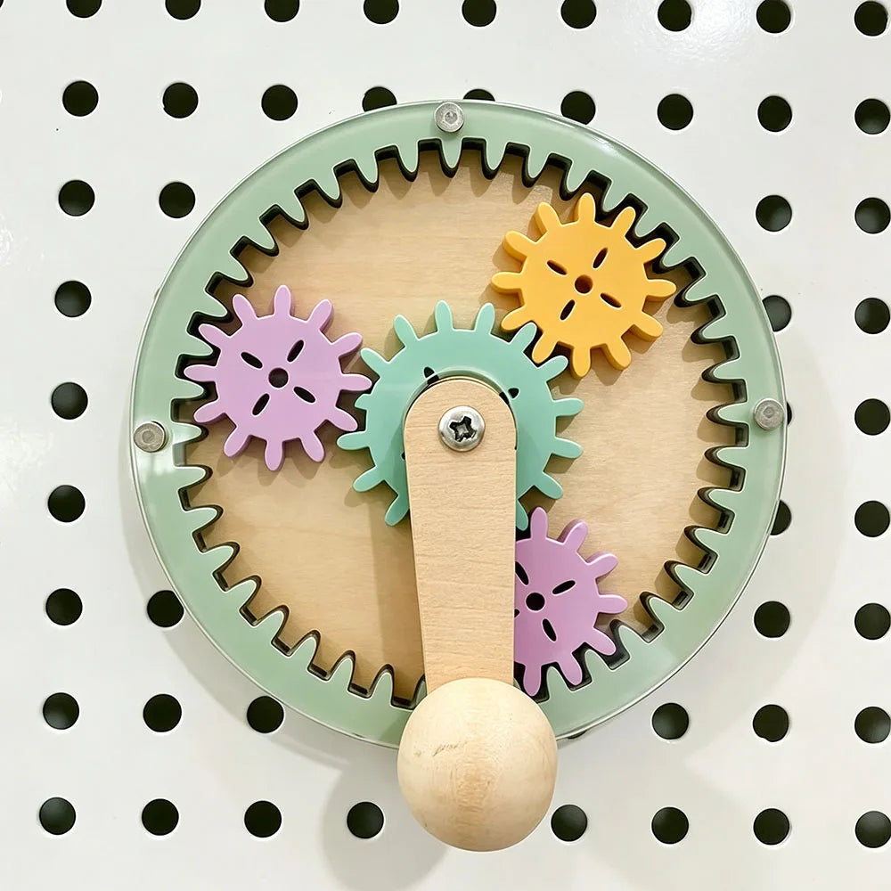 A wooden busy board featuring colorful gears and a wooden knob for fine motor skill development.