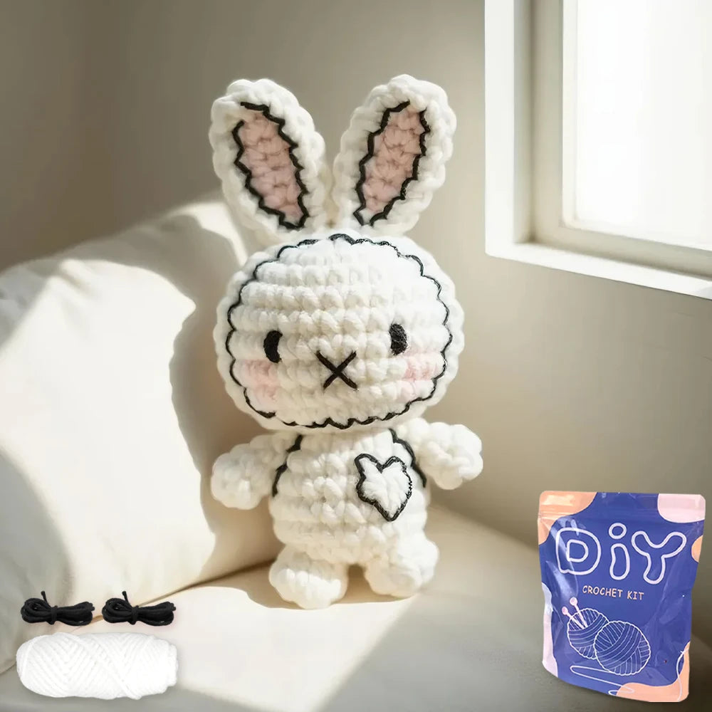 A white crocheted bunny amigurumi with pink accents sitting on a light-colored sofa.