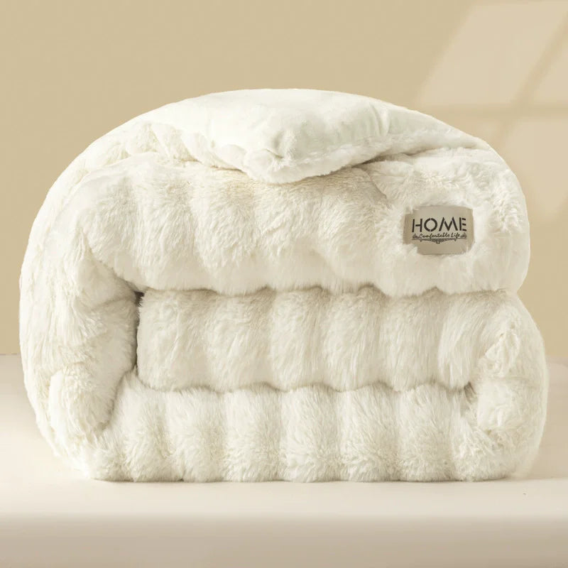 A thick, white plush winter comforter or quilt folded neatly on a light surface.