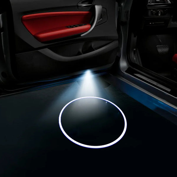 Car door logo projector lights illuminating the interior of a car door panel.