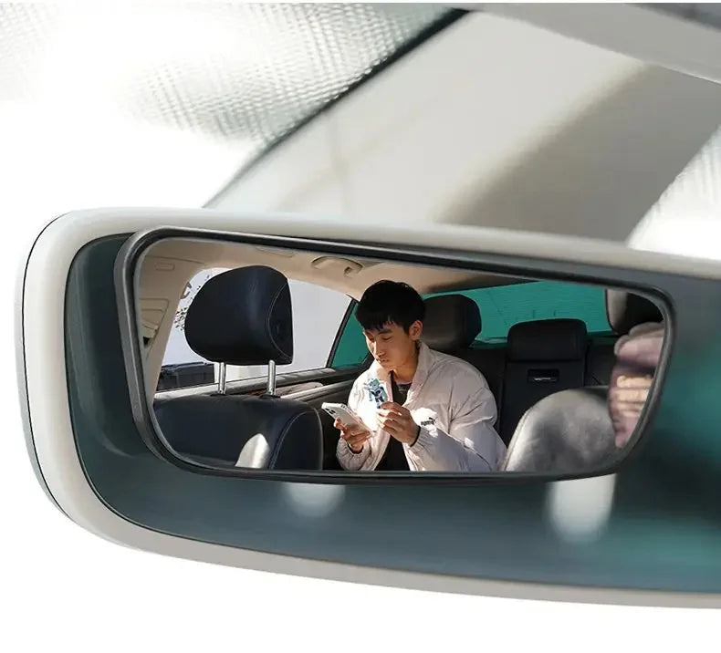Interior view of a car showing a 360° adjustable pair of blind spot mirrors mounted on the door frame.