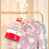 A set of adjustable baby clothes hangers with pink and green fabric hangers displayed on a gold-toned rack.