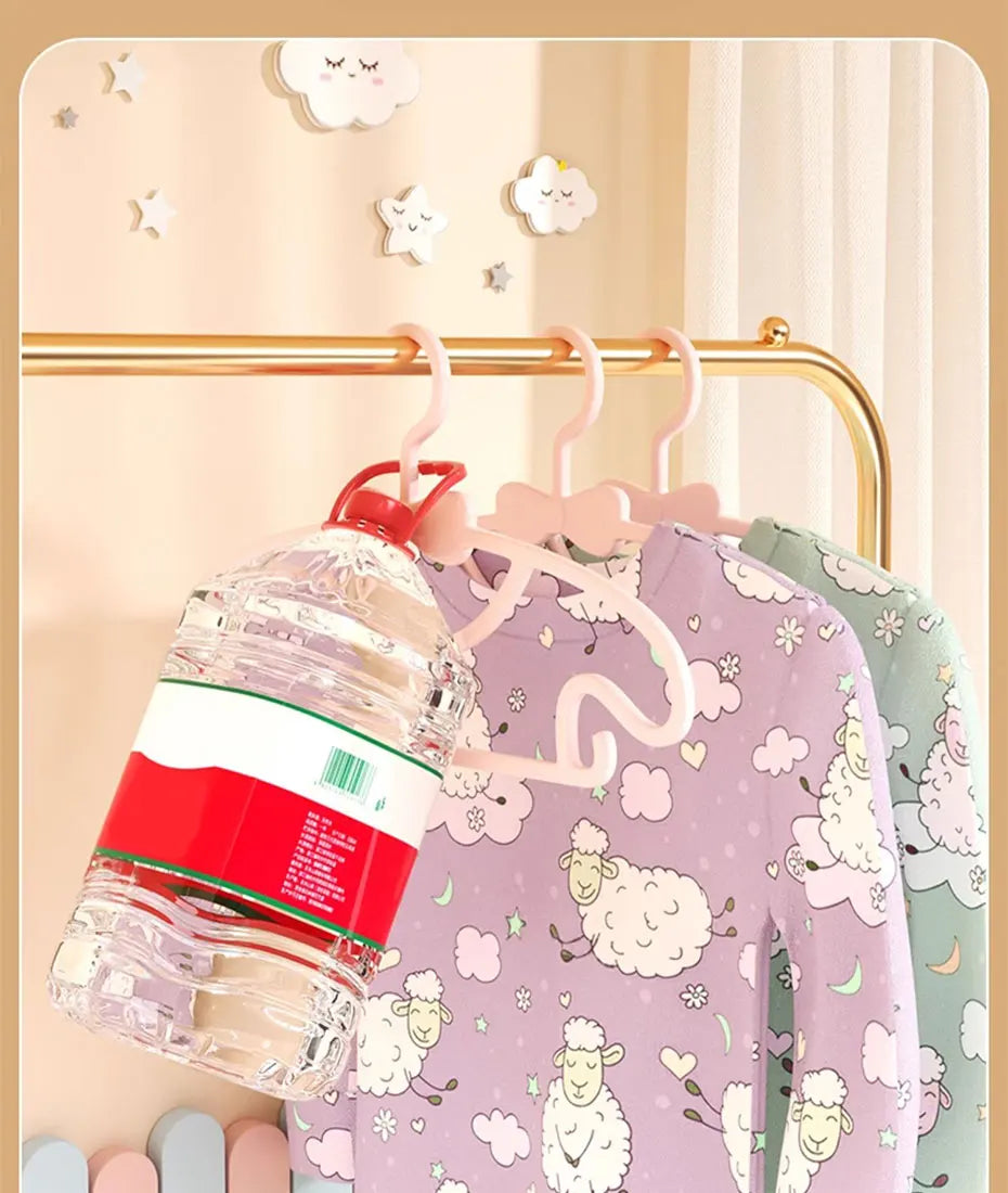 A set of adjustable baby clothes hangers with pink and green fabric hangers displayed on a gold-toned rack.
