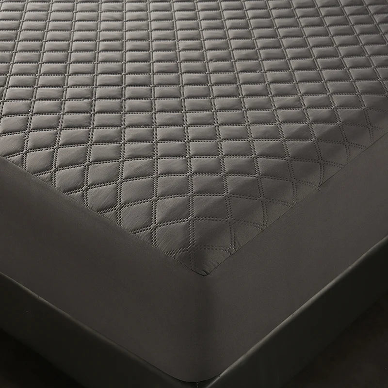A close-up view of a dark gray quilted waterproof mattress protector with deep pockets.