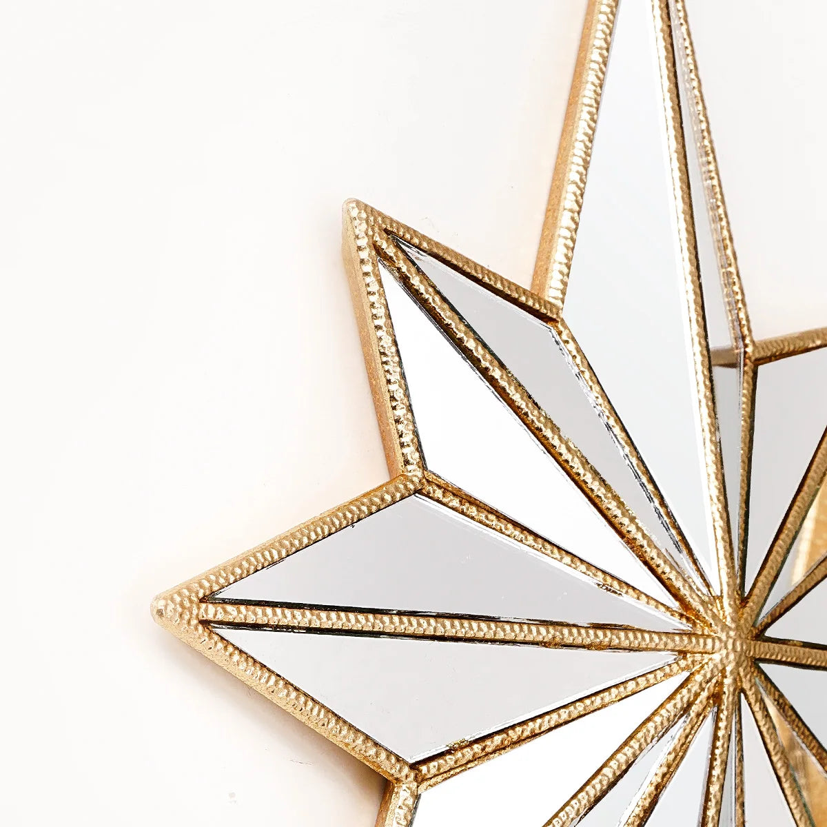 A close-up of an octagonal star resin wall mirror with gold trim and reflective surface.