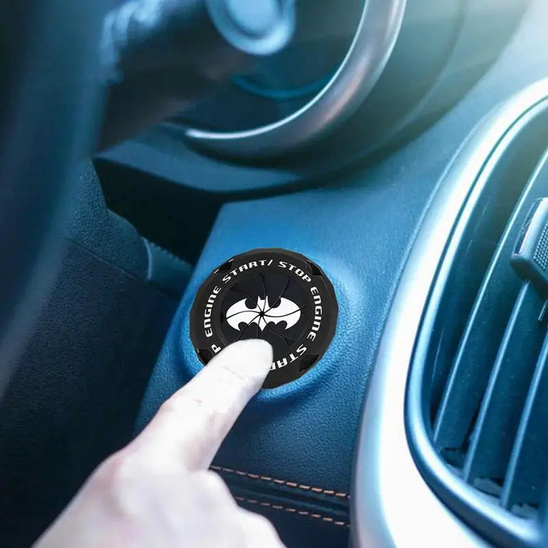 A hand presses a push start button cover with a supercar spin design on a car's dashboard.