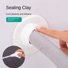 A hand is applying white sealing clay to an AC hole or pipe gap using a tool.