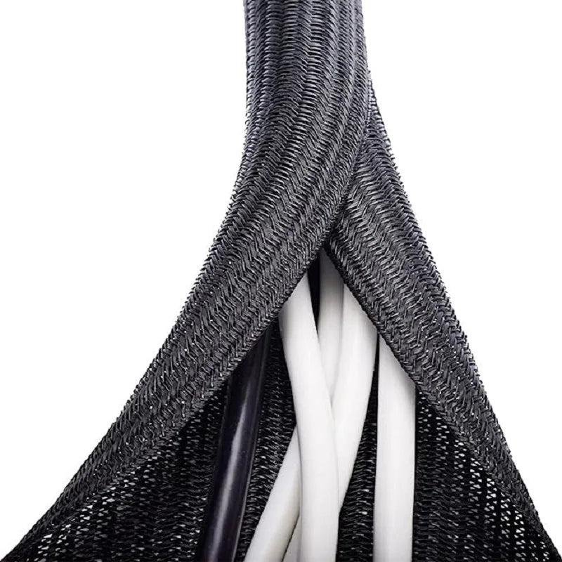 Close-up view of a black braided cable sleeve with white wires inside, used for desk and home organization.