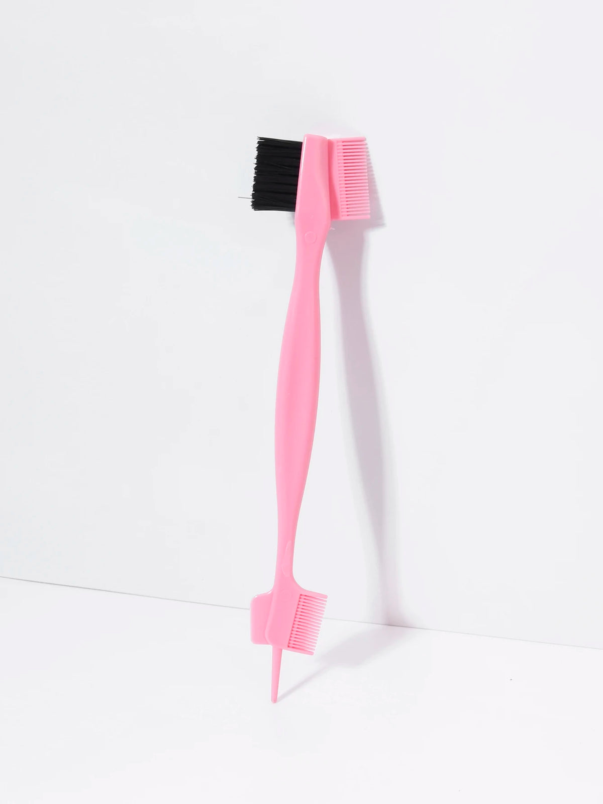 A pink precision edge control brush and comb set with black bristles, shown against a white background.
