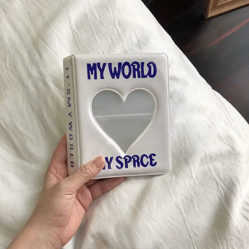 A white mini photo album titled My World with a heart-shaped clear window on the cover