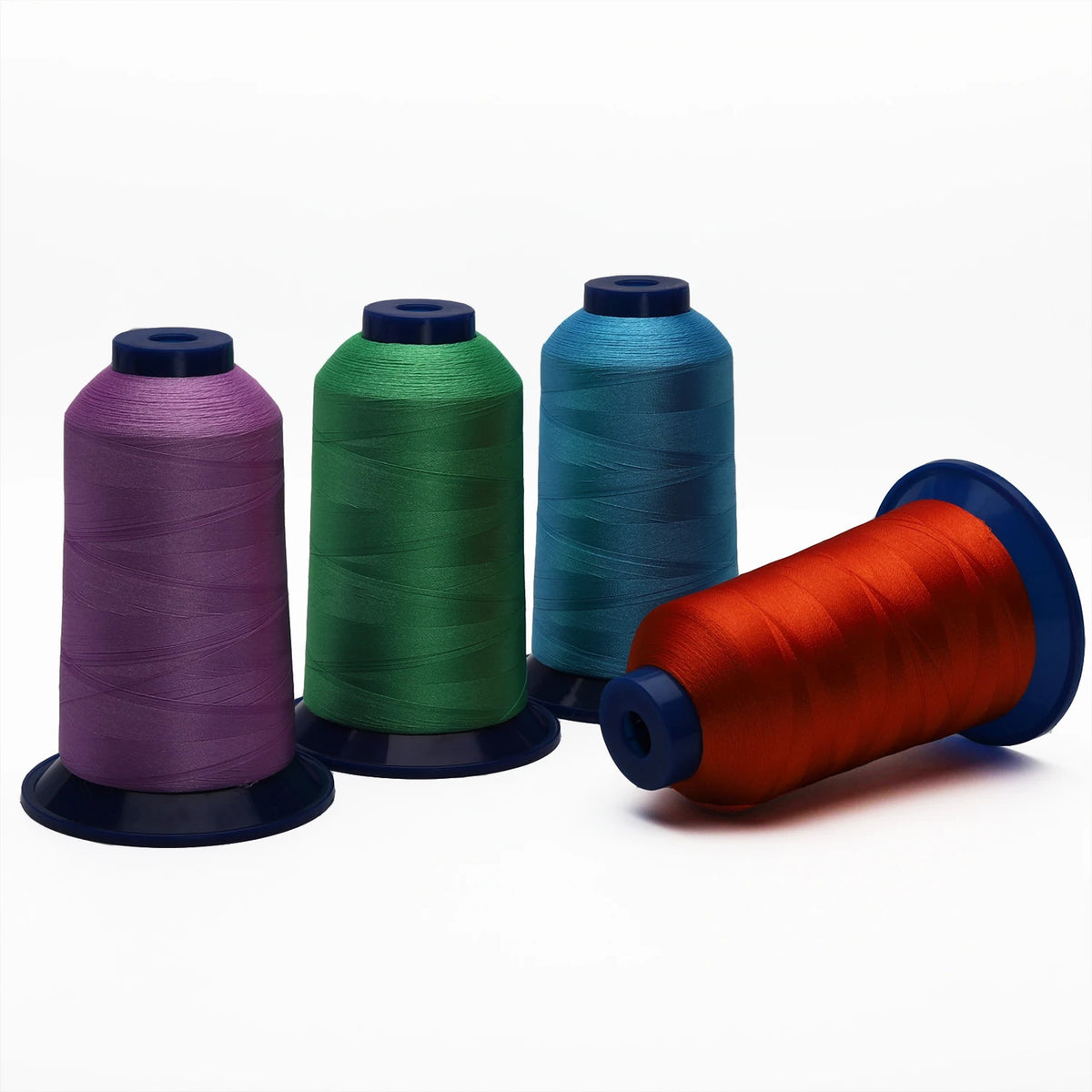 Three spools of polyester embroidery thread in purple, green, and teal colors displayed on a white background.