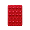 A red silicone suction pad with multiple circular indentations for phone mounts.