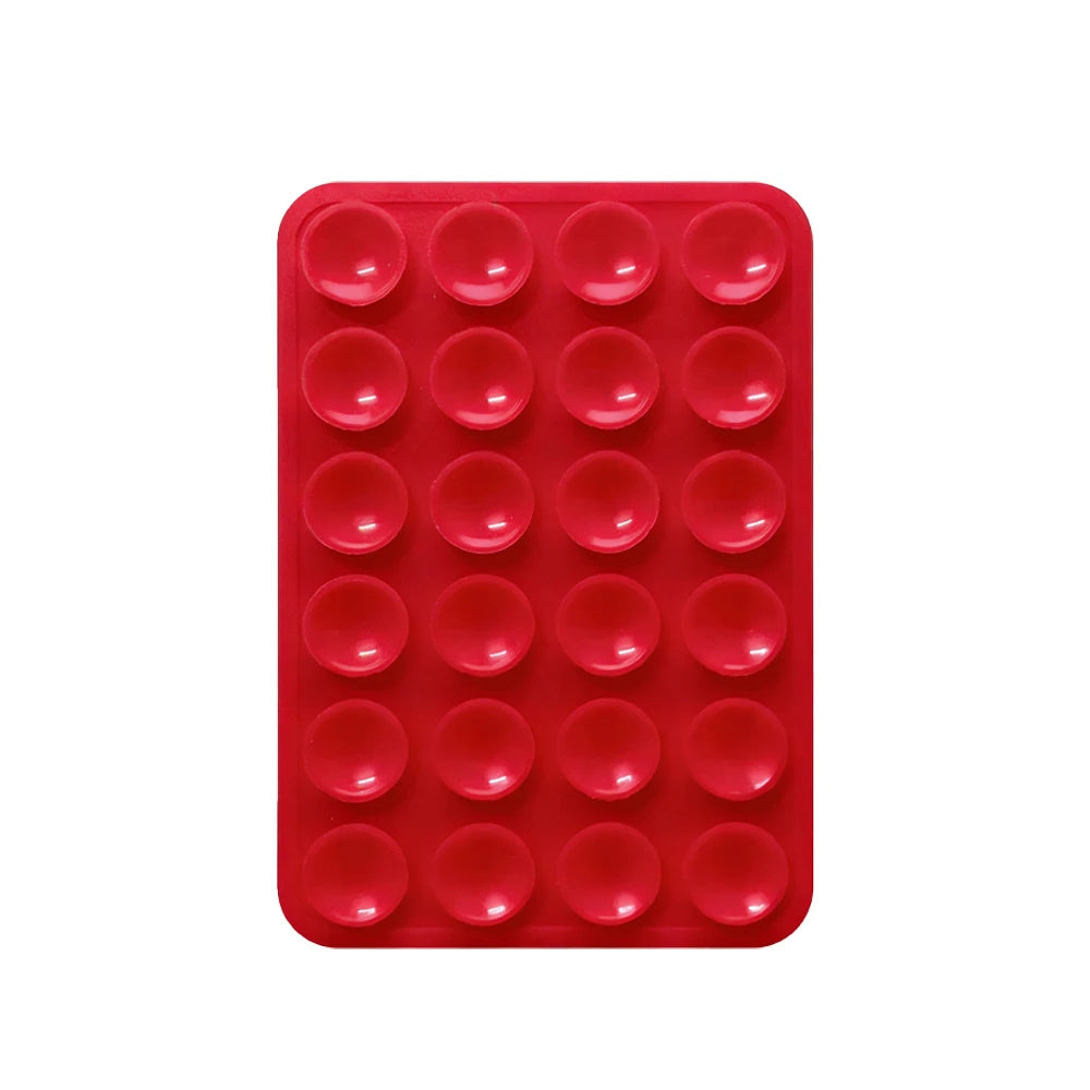 A red silicone suction pad with multiple circular indentations for phone mounts.