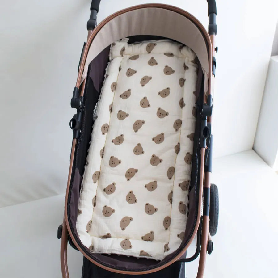 A beige and brown cartoon bear stroller cushion is shown inside a dark brown carrier bag.