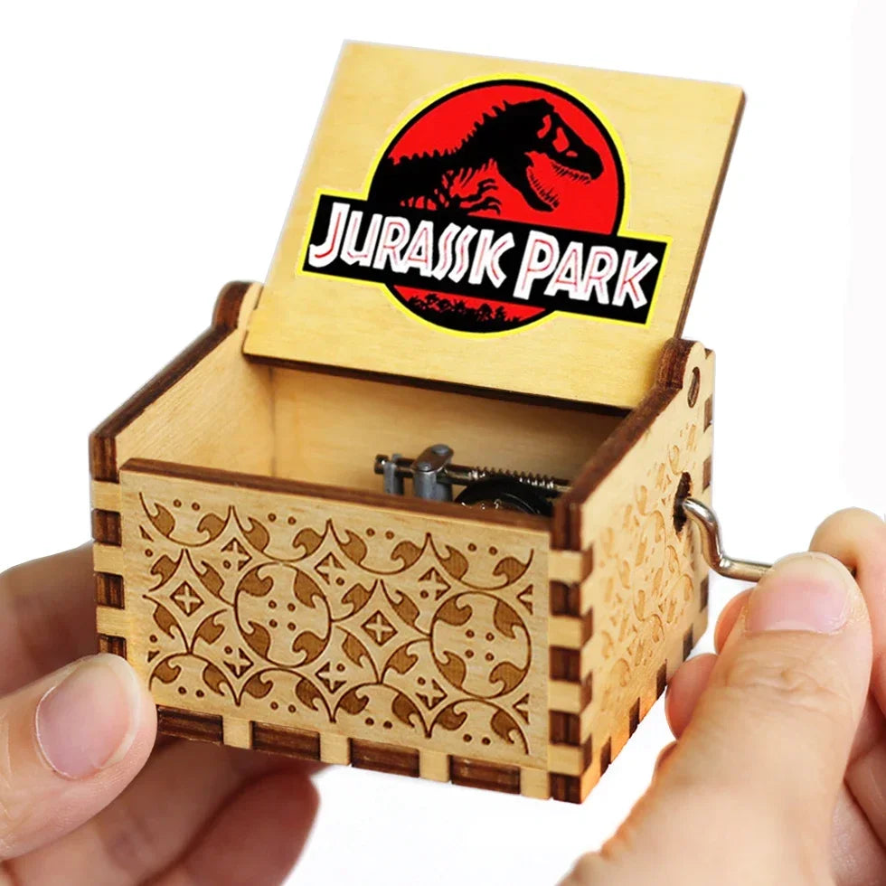 A wooden music box with a lid featuring the Jurassic Park logo, being held in a hand.