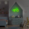 A neon sign shaped like a tractor in green and yellow illuminates a wall above a child's bed.