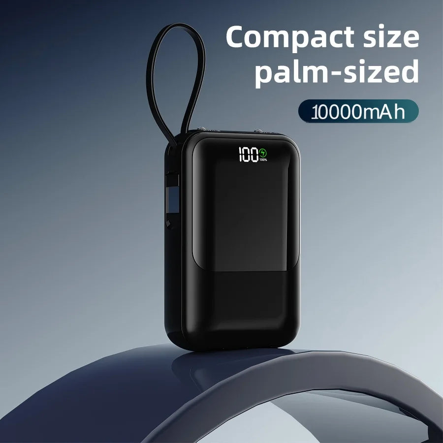 Schwarze, palmkissenförmige Powerbank mit Batteriespeiseanzeige und flexiblem Ring auf blauem Untergrund.