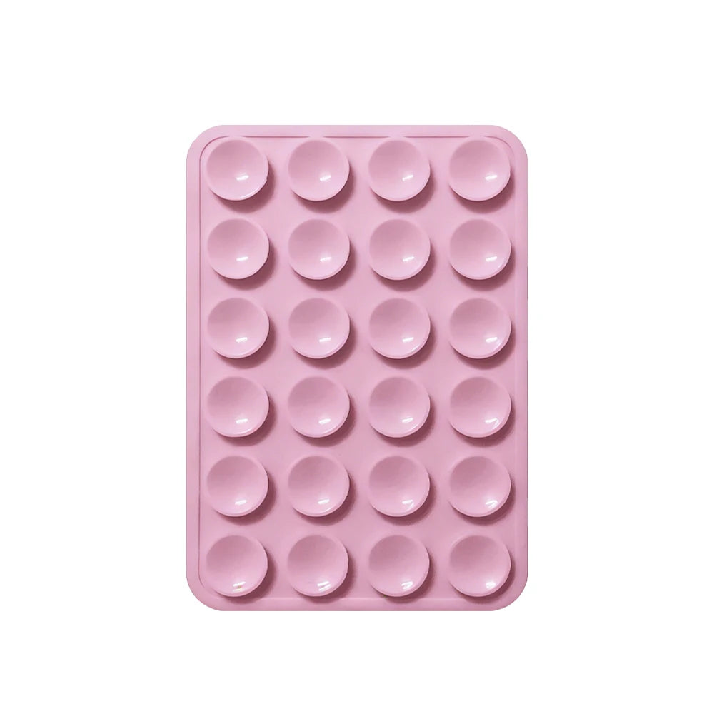 A pink silicone suction pad with multiple circular indentations for phone mounts.