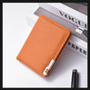 A slim vertical orange leather wallet with a silver clasp resting on a white surface next to a black pen and a magazine.