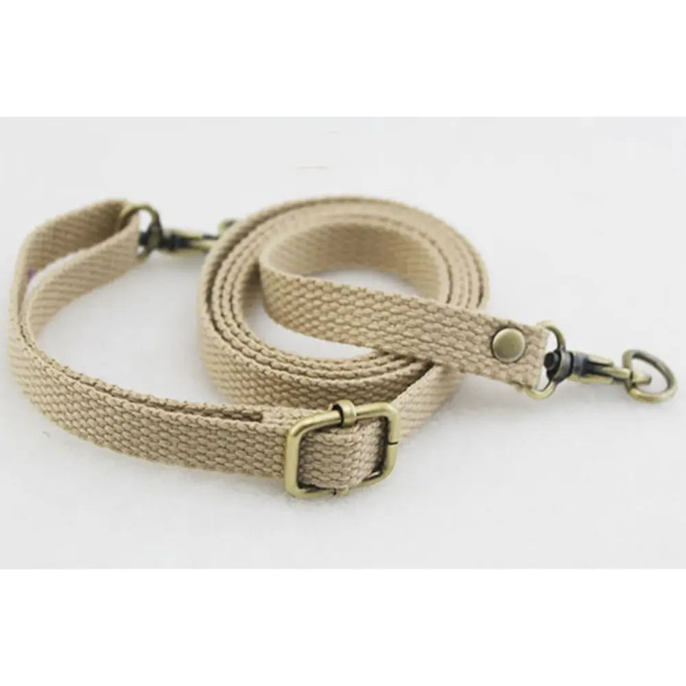 A beige canvas shoulder strap with a brass buckle is shown against a white background.
