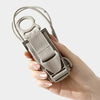 A hand holds an adjustable luggage strap with a quick-release buckle, showing the strap and buckle mechanism.