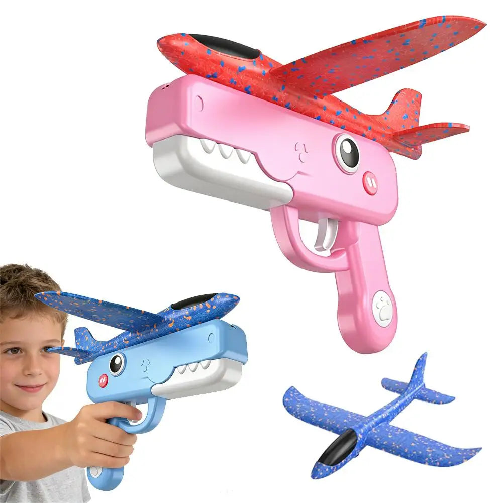 A pink foam catapult toy shaped like a dinosaur head with red and blue patterned airplane wings and a blue airplane model.
