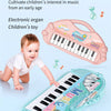 A pink electronic organ toy piano with a microphone and a light blue keyboard is shown next to a baby.